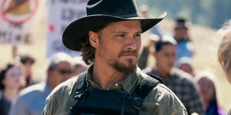Man in a black cowboy hat and tactical vest labeled 'U.S. Marshal' stands at a protest, looking to the side.
